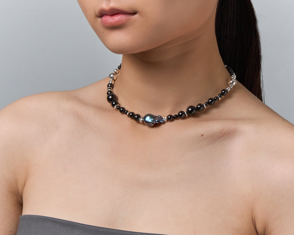The Black Pearl worn as a necklace, the dark baroque pearl sitting at the centre of the collarbone