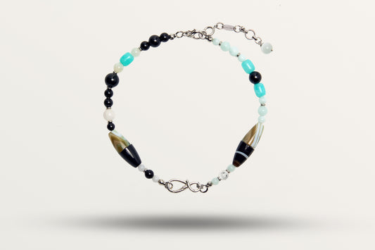 The Serenity as a necklace, one closed loop of black and turquoise stones with two striped barrel beads
