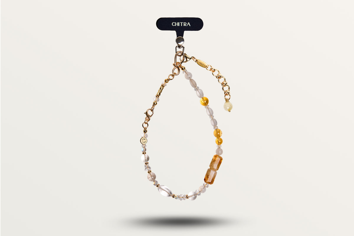 The Golden Winter hanging as a phone charm, honey and milky stones on gold-tone hardware