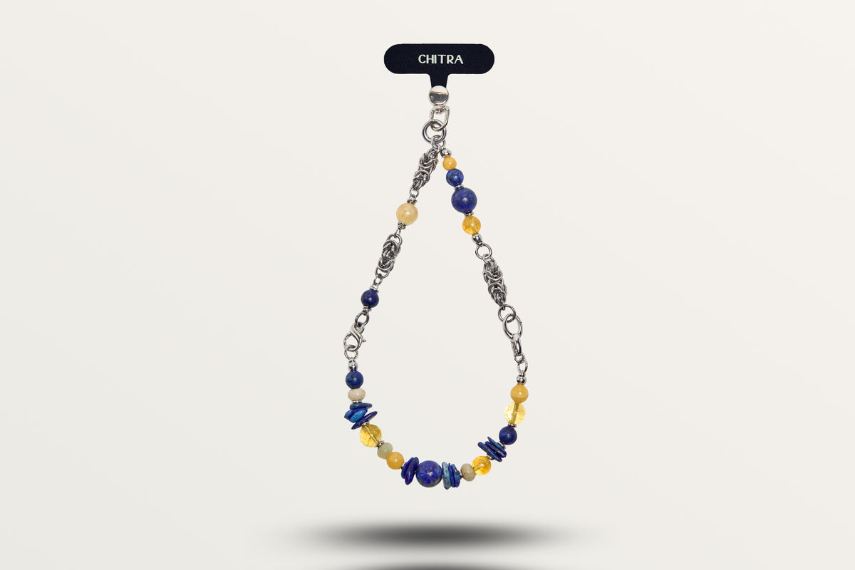 The Moon Phase hanging as a phone charm, deep blue and yellow stones on a woven steel chain