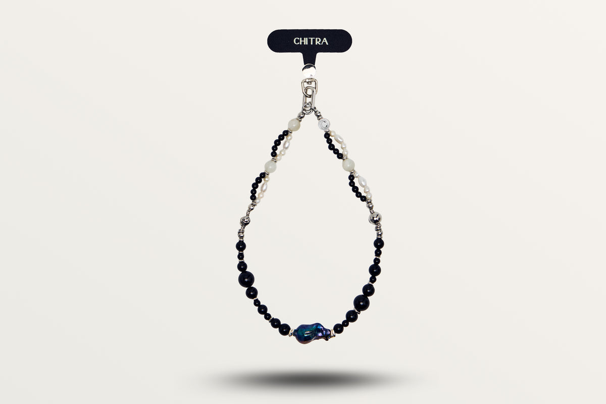 The Black Pearl hanging as a phone charm, black stones and white pearls