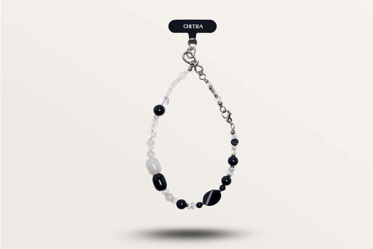 The Yin Yang hanging as a phone charm, black and white stones